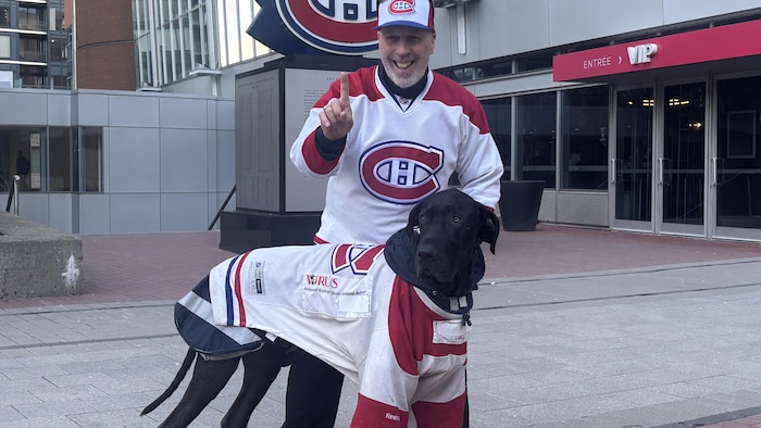 Un partisan avec son chien, tous les deux portent un chandail des Canadiens.