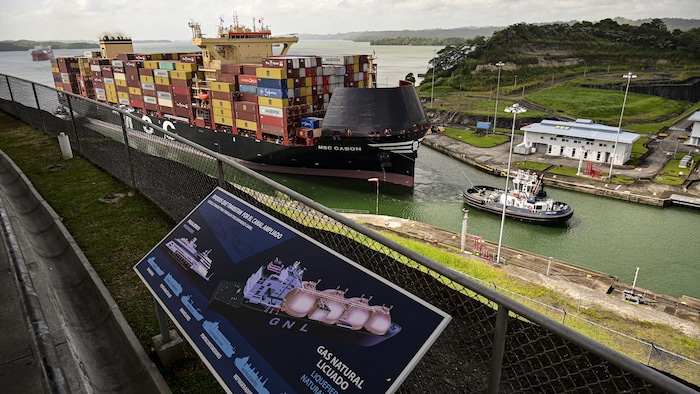 Un porte-conteneurs est remorqué dans le canal.