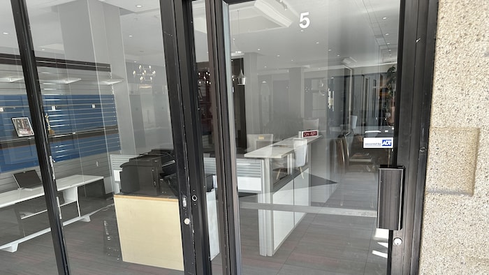 Un local avec des mobiliers de bureau derrière une porte de vitre.