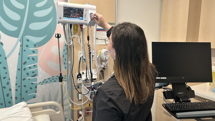 Une infirmière se prépare à prendre la température corporelle d'un patient.