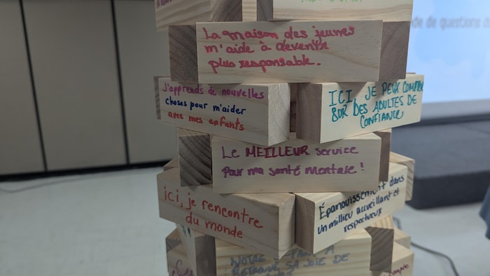 Des phrases en lien avec le milieu communautaire fragile sont écrites sur des blocs du Jenga.