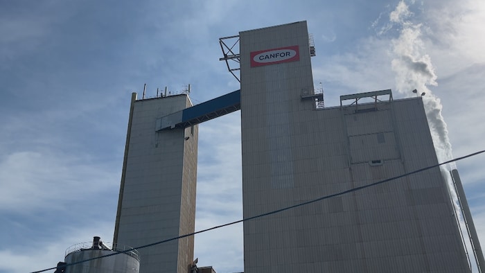 Une usine avec le logo de Canfor par laquelle de la fumée sort.