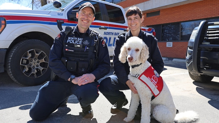 Un chien en compagnie de deux policiers.  