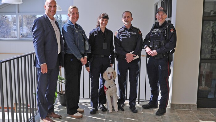 Un chien en compagnie de deux policiers.  
