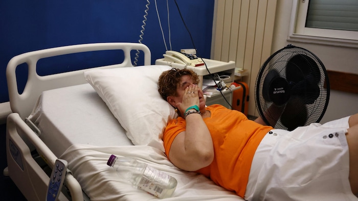 Une patiente sur un lit d'hôpital, visiblement accablée de chaleur.