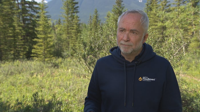 Simon Black est devant une forêt et des montagnes.