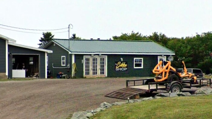 Un petit bâtiment en long, vert, avec une enseigne.