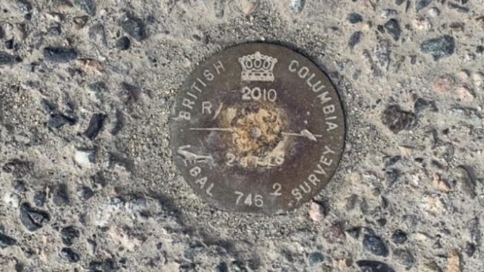 Un sceau de bronze dans le ciment avec la mention ''arpentage Colombie-Britannique''.