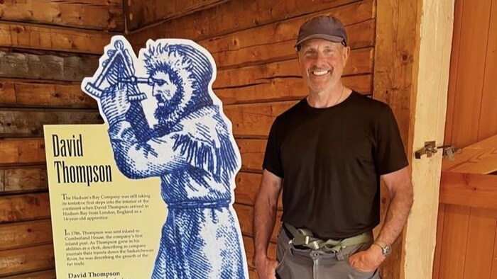 Un homme devant un panneau sur David Thompson.