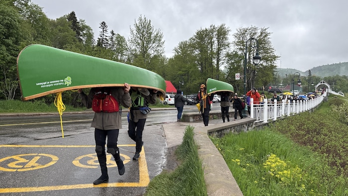 Des gens font un portage de canots dans une rue.