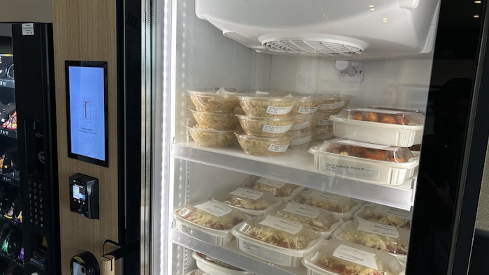 Un réfrigérateur de type « machine distributrice » propose des plats d'un traiteur.
