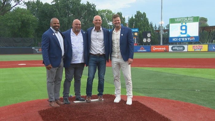 Quatre hommes dans un stade de baseball.