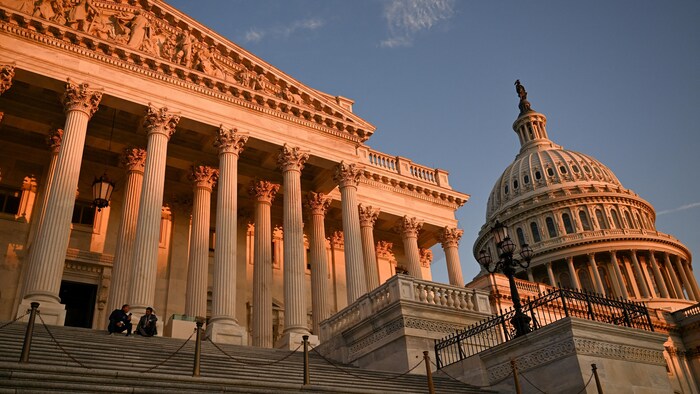 Deux personnes sont assises sur les marches du Capitole, à Washington.