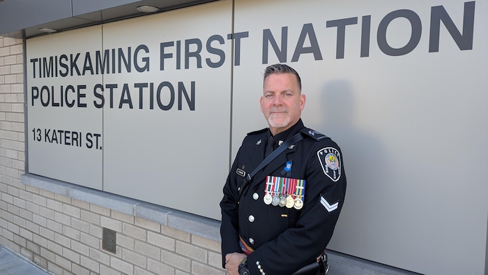 François Savage pose devant le poste de police en uniforme, avec ses médailles.
