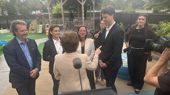 Une photo de Christine Fréchette, de dos, discutant avec ses collègues. 