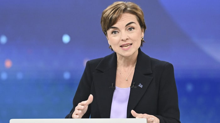 Christine Fréchette s'exprime derrière son pupitre en faisant un geste de la main.