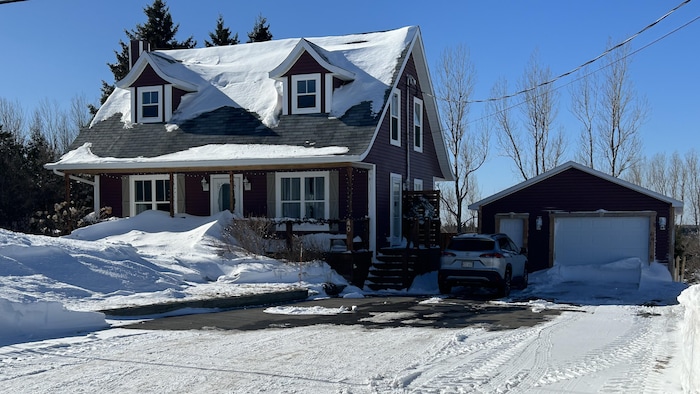 Une maison en hiver, avec un garage détaché.