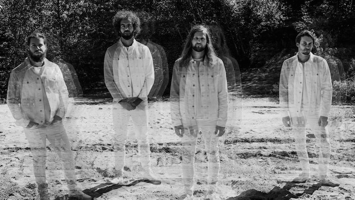Les quatre membres du groupe Caravane photographiés à l'extérieur avec un effet évanescent