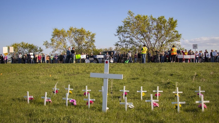 Un rassemblement devant des croix en hommages aux victimes.