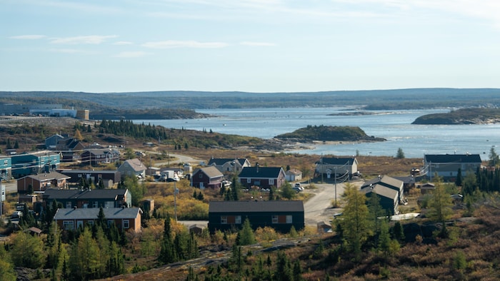 Le village de Kuujjuak au bord de l'eau, entouré de forêt.