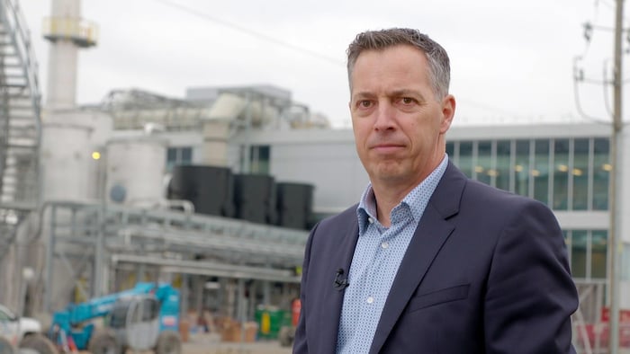 Carl Desharnais devant une usine.