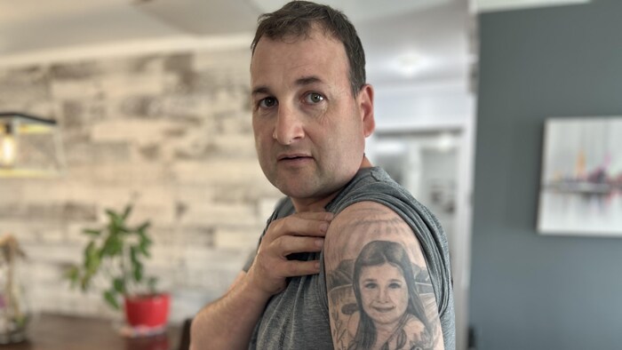 Un homme montre un tatouage sur son bras.