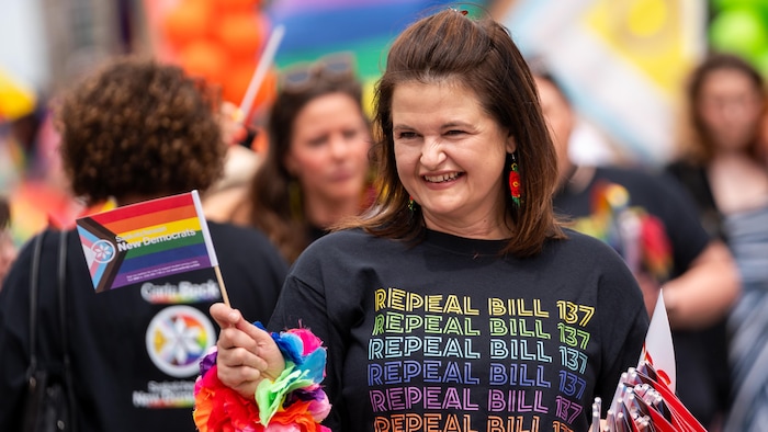La cheffe du Nouveau Parti démocratique de la Saskatchewan, Carla Beck, porte un chandail en soutien à la communauté LGBTQ+ demandant l'abrogation de la Loi sur les droits parentaux lors du défilé de la Fierté.