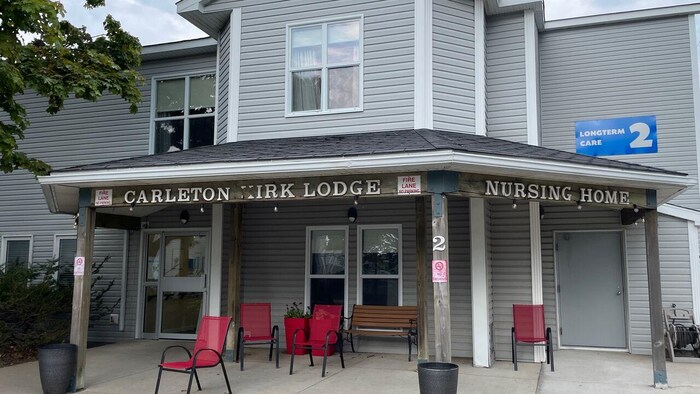 Entrée principale de Carleton-Kirk Lodge. Des chaises rouges sont devant l'entrée, avec personne d'assis dedans.