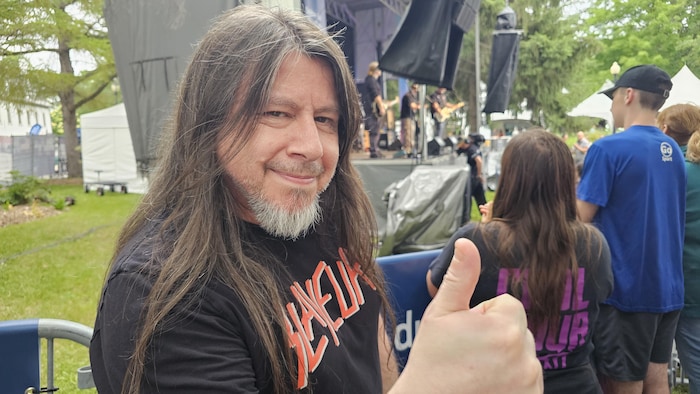 Carlos Araya smiles on the camera and lifts her thumb in the air.