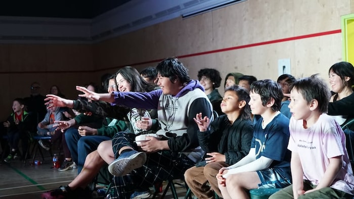 Des jeunes regardent un match de lutte.