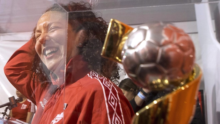 L'ancienne internationale canadienne, Carmelina Moscato, à côté de la Coupe du monde féminine de soccer.