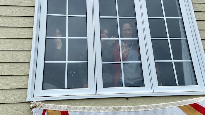 Carmen André et sa famille sont à leur fenêtre de leur maison.