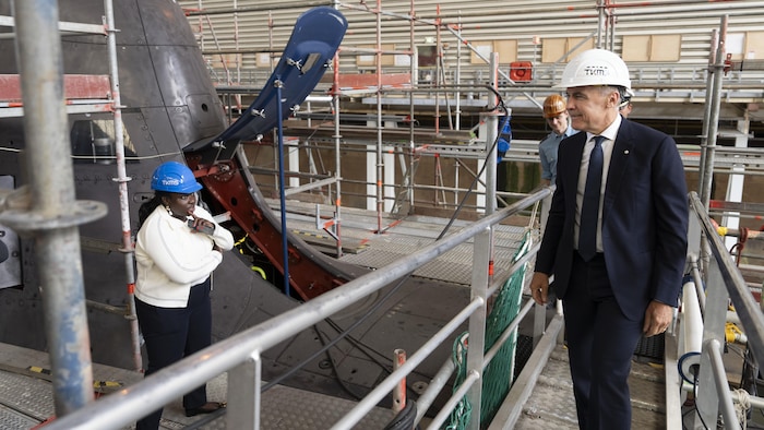 Mark Carney passe devant un sous-marin en maintenance, entouré d'employés de l'usine.