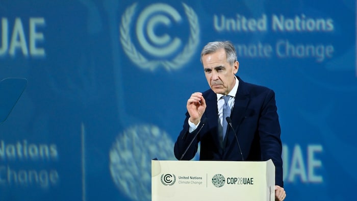 M. Carney parle derrière un microphone dans une conférence de l'ONU sur le climat.