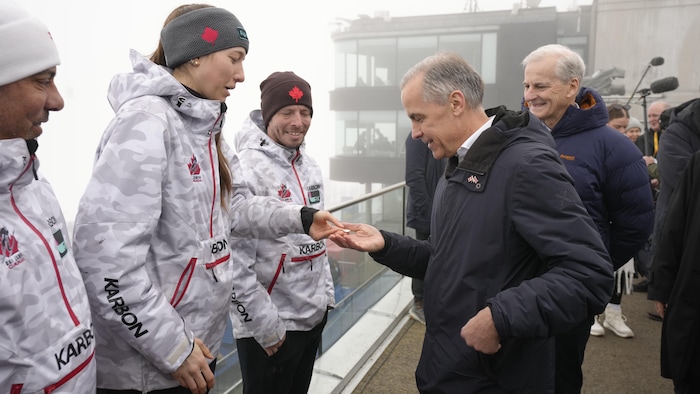 Mark Carney se fait donner une épingle par Nicole Maurer.