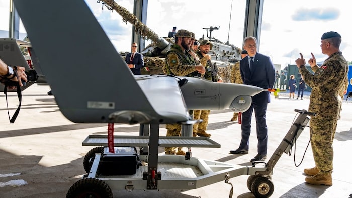 Mark Carney discute avec un soldat devant un drone.