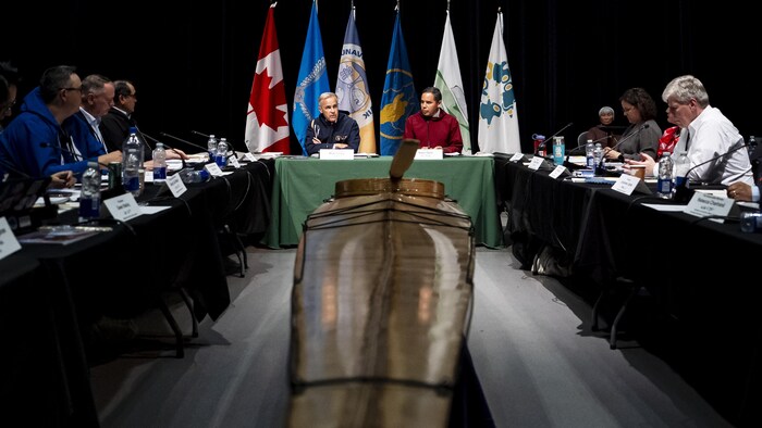 Mark Carney et Natan Obed sont entourés de plusieurs personnes autour d'une table.