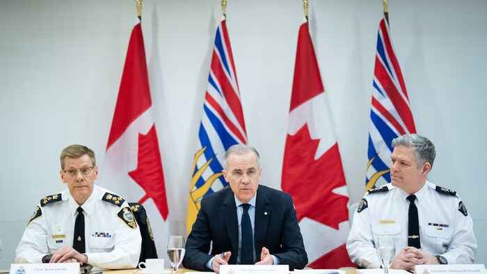 Le premier ministre Mark Carney s'exprime lors d'une table ronde avec la police, entouré du chef de police de Surrey, Norm Lipinski, à gauche, et du sous-commissaire de la GRC, Dwayne McDonald, à droite, au quartier général de la division E de la GRC à Surrey, en Colombie-Britannique, jeudi.