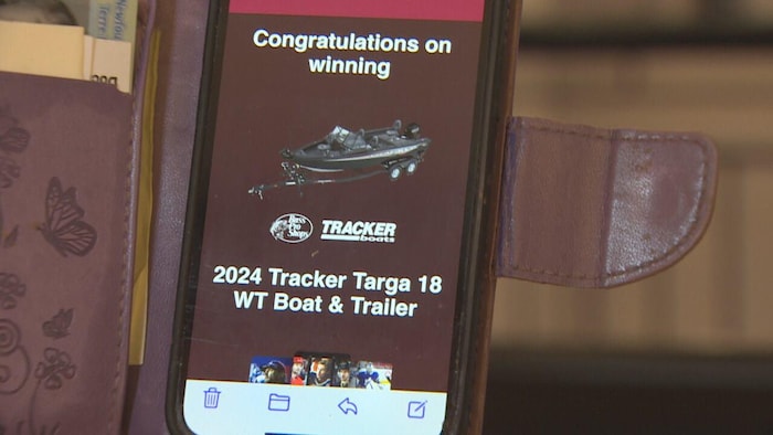 Un téléphone portable où figure un message indiquant qu'un bateau et une remorque ont été gagnés.