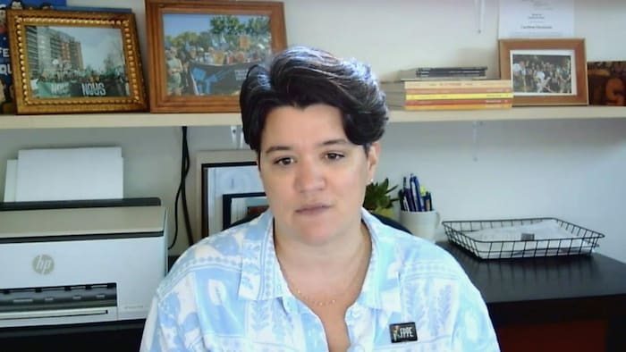 Une femme fixe la caméra dans son bureau.
