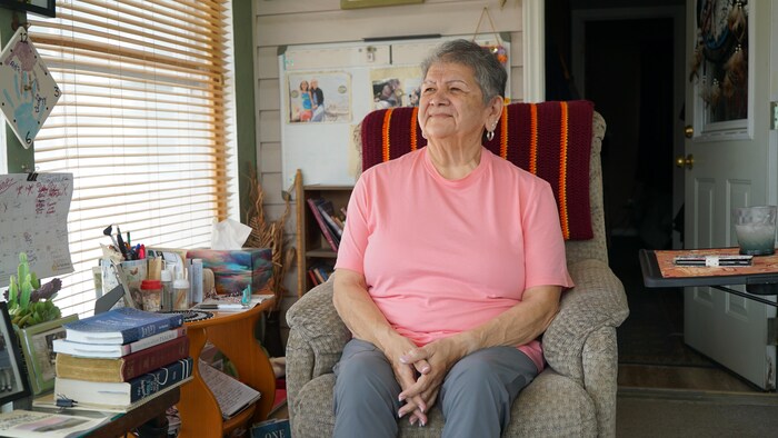 Carole Gagnon dans son salon, assise dans un fauteuil. 