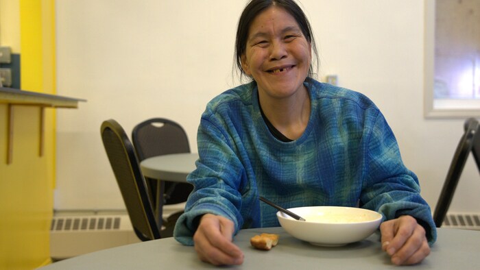 Une femme assise à une table devant un bol de soupe.