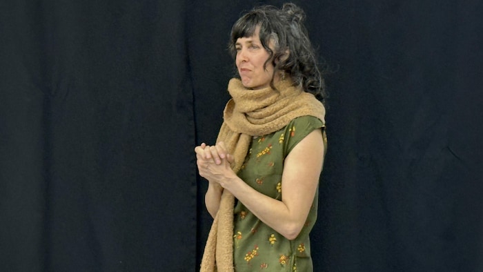 Les deux mains de Caroline Dufour sont jointes et elle semble écouter avec attention.