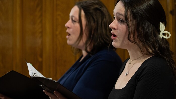 Deux femmes chantent avec un livre dans les mains.