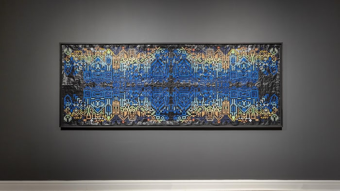 Un tableau dans les tons de bleu est accroché à un mur.