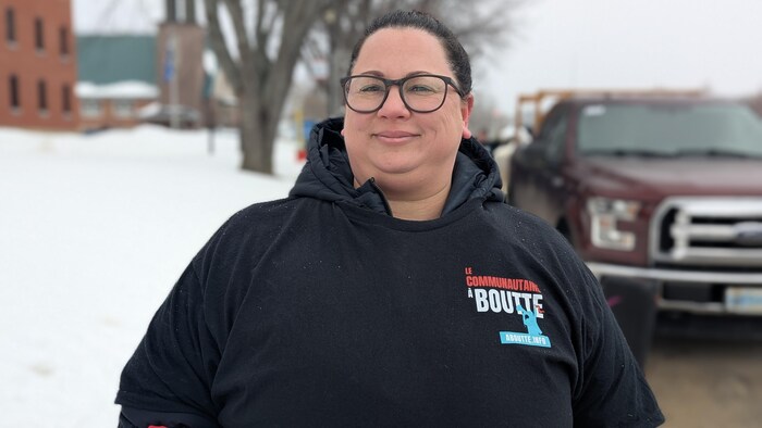 Caroline Nadeau pose dehors, devant l'hôpital de Ville-Marie, avec son chandail « Le communautaire à boutte ».