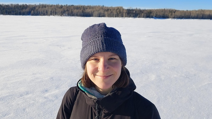 Elle pose en hiver devant un lac gelé recouvert de neige.