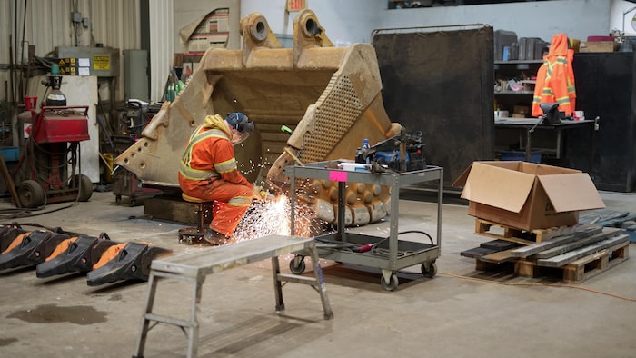 Un homme fait de la soudure dans un atelier d'équipement lourd.