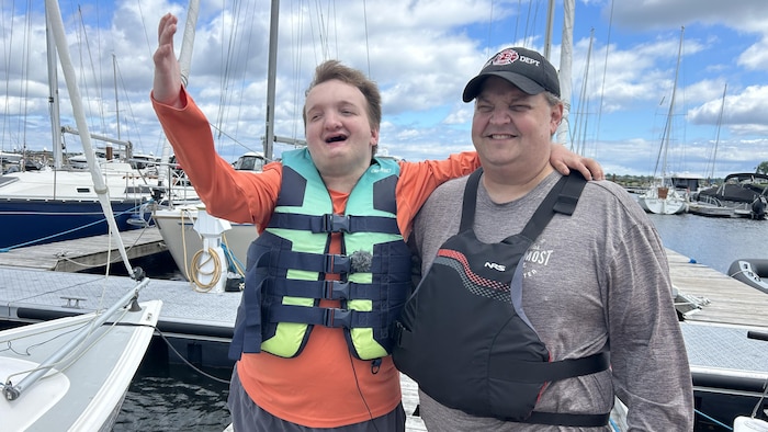 Un père et son fils sur le quai, près de plusieurs voiliers.