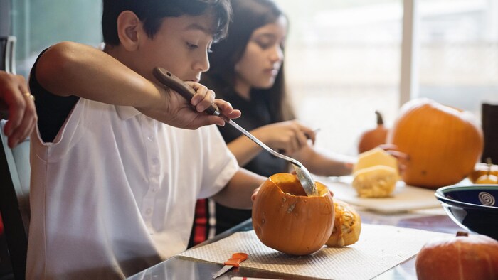 Deux enfants sont en train d'éviter et de couper des citrouilles.